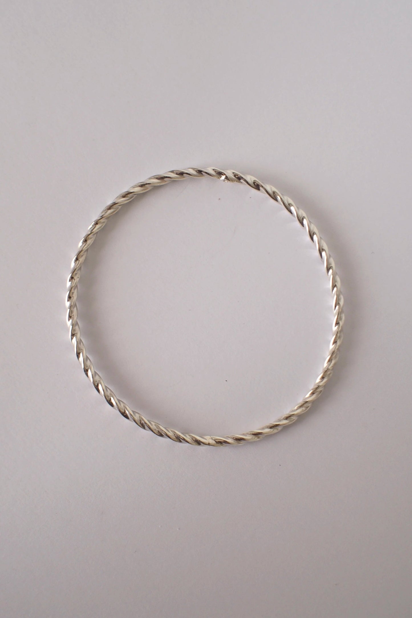 Silver twist bangle on a light gray background