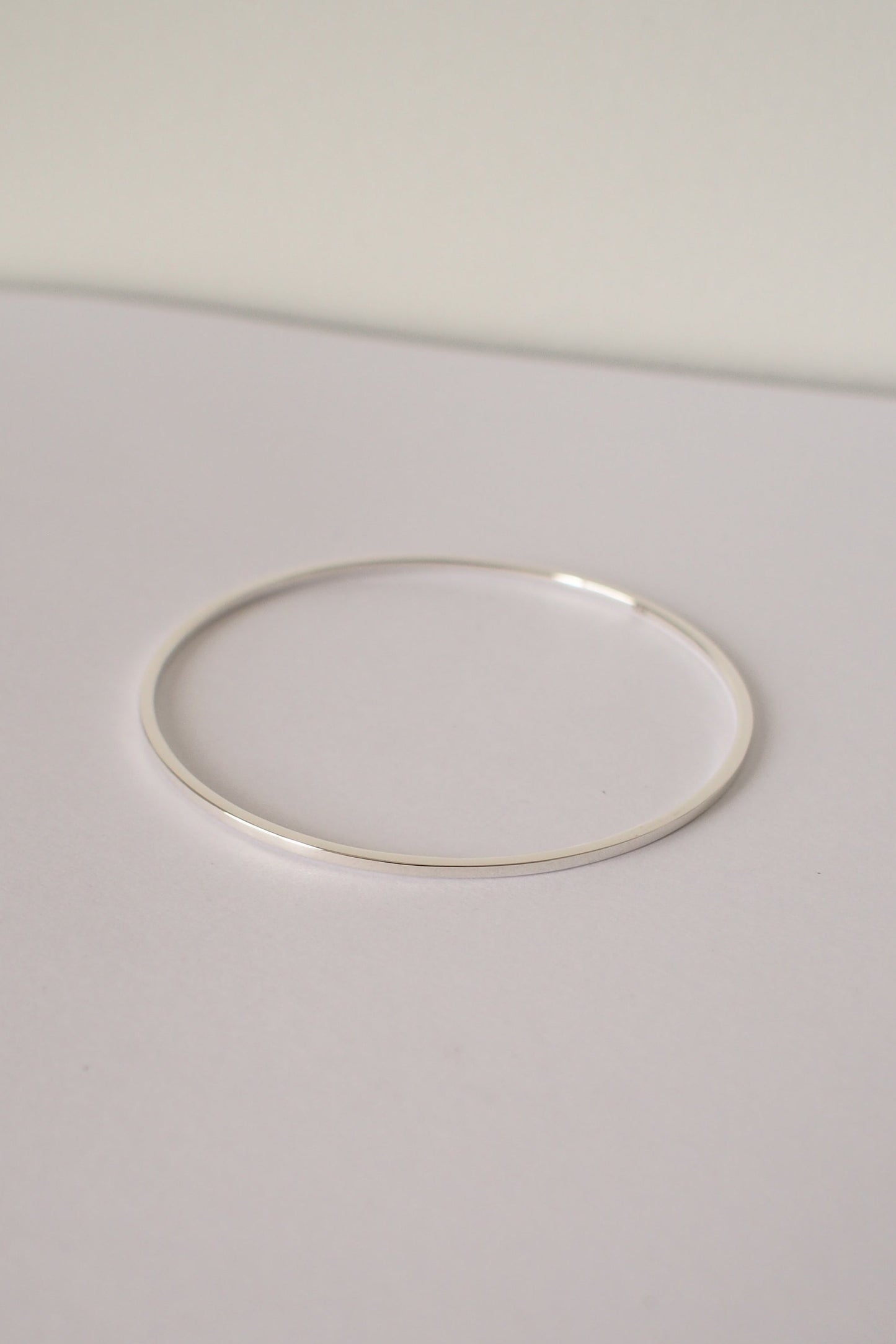 Silver square bangle on a light gray background