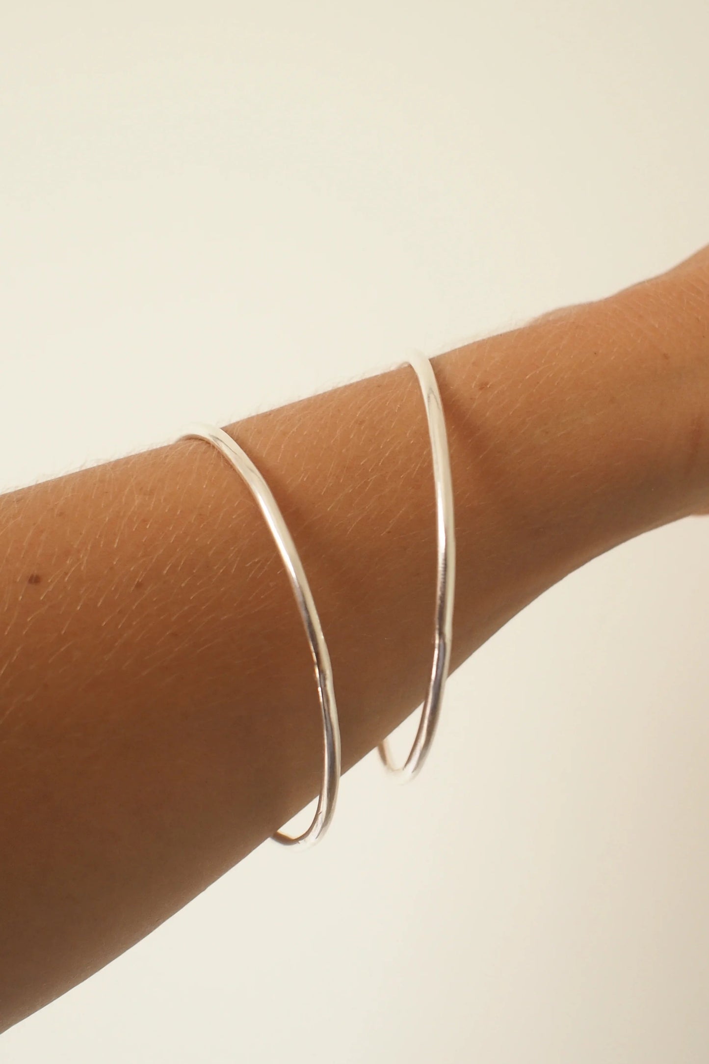 Silver bracelet on a person's wrist against a plain background