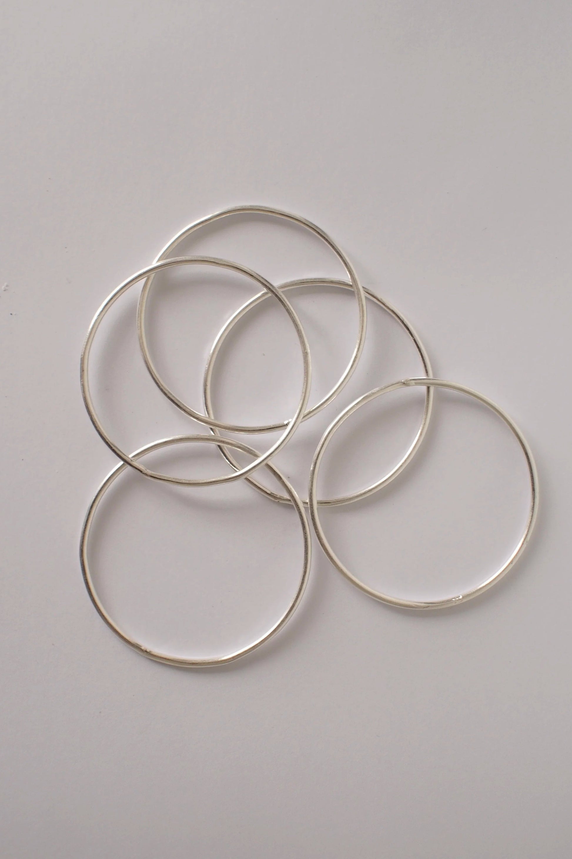 Silver bangles on a white surface