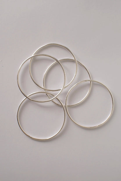 Silver bangles on a white surface