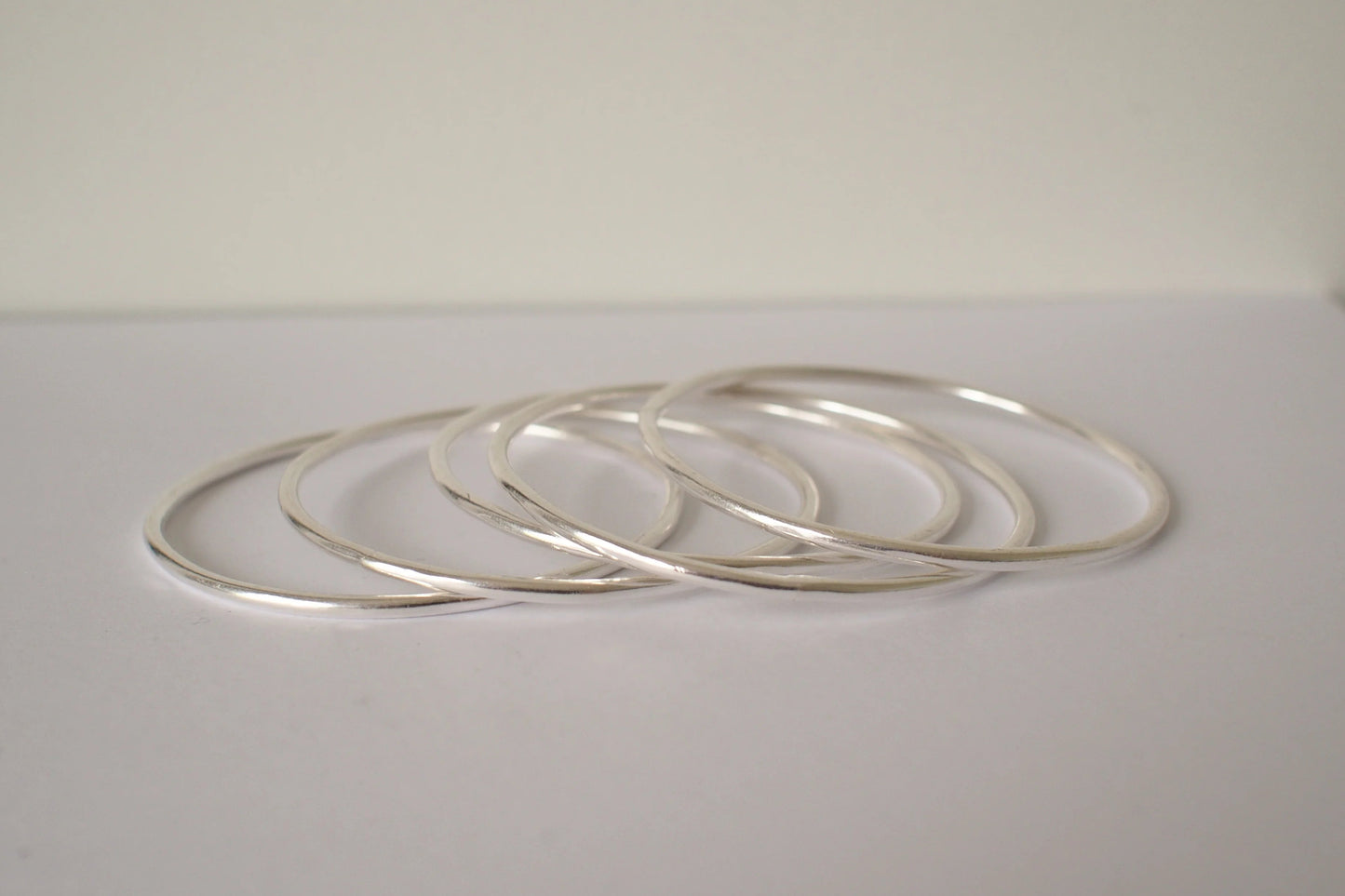 Set of silver bangles on a light gray surface