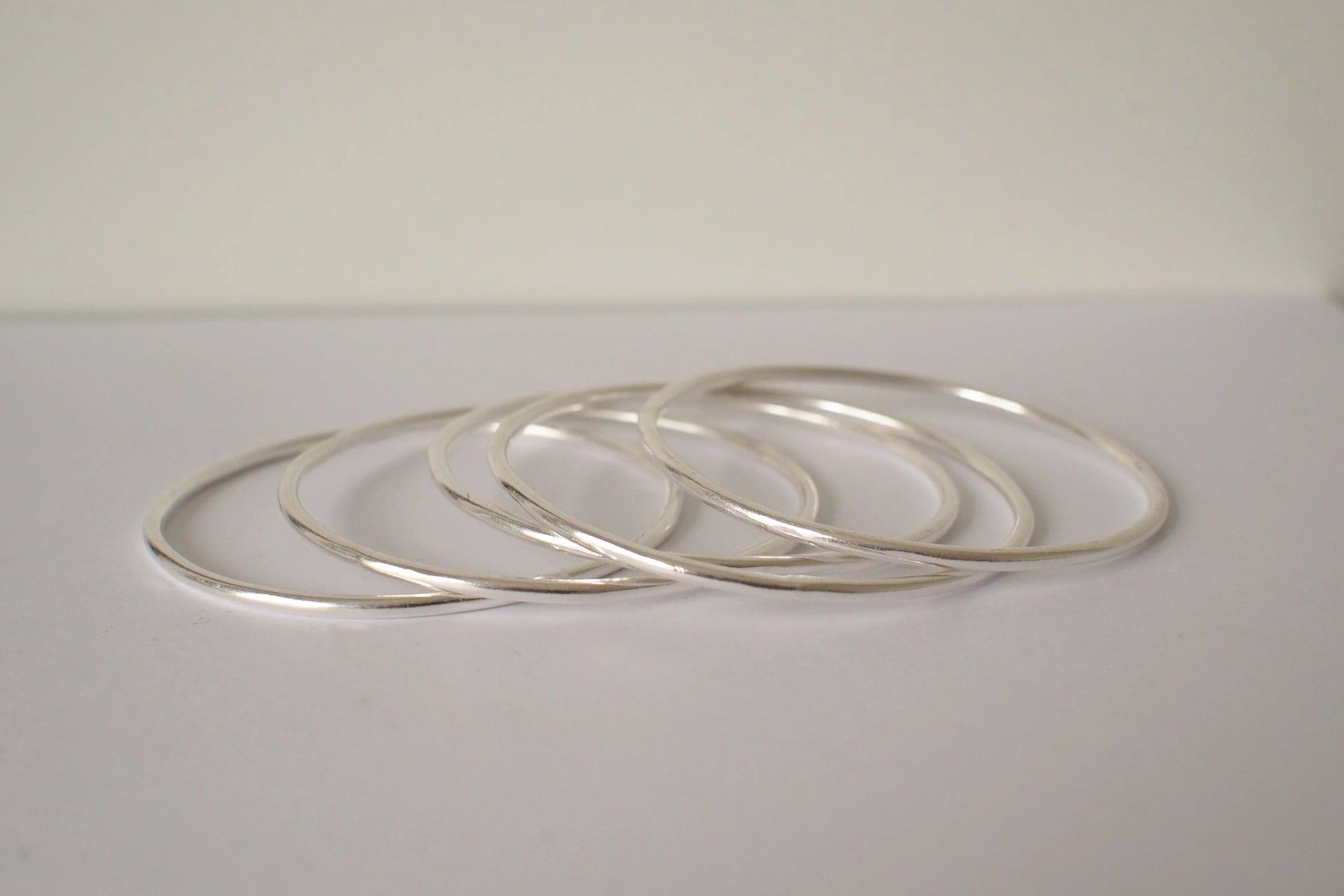 Set of silver bangles on a light gray surface