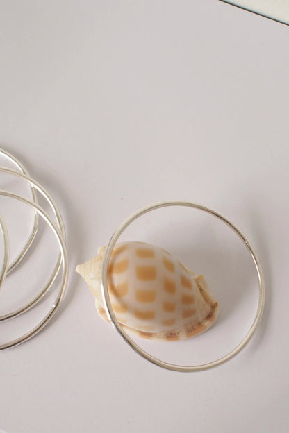 Shell inside a silver bangle on a white surface