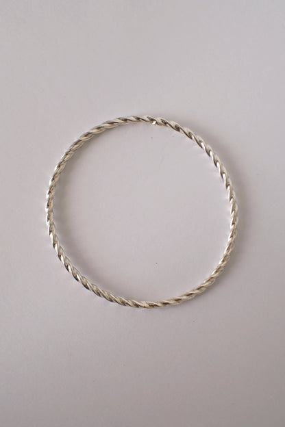 Silver twist bangle on a light gray background