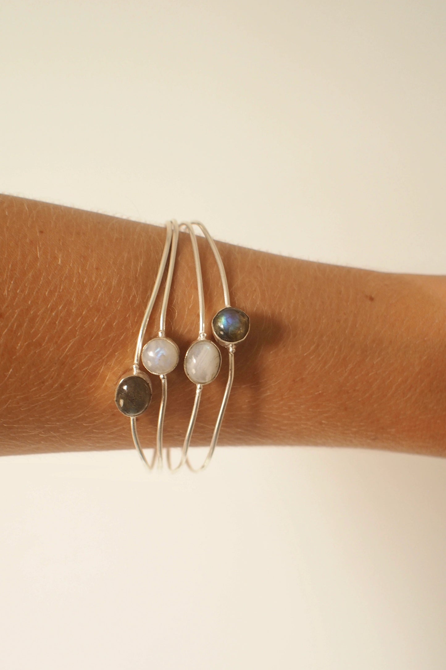 Ocea bangle with gemstones on a wrist against a beige background