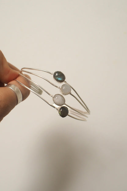 Silver ocea bangle with three stones held against a plain background