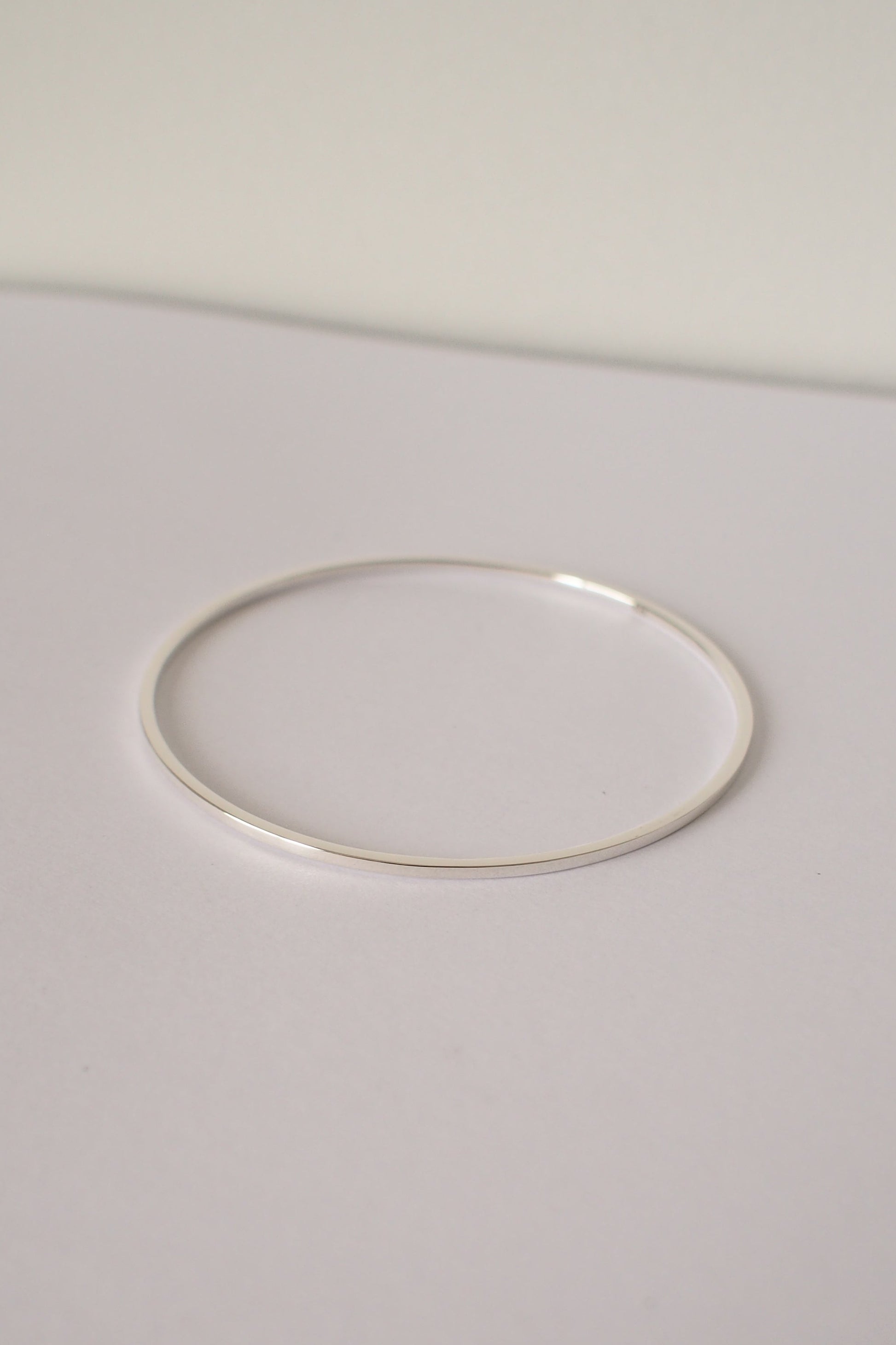 Silver square bangle on a light gray background