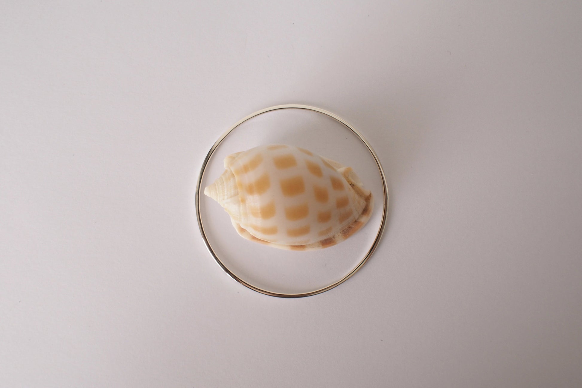 silver square bangle with a shell design on a white background