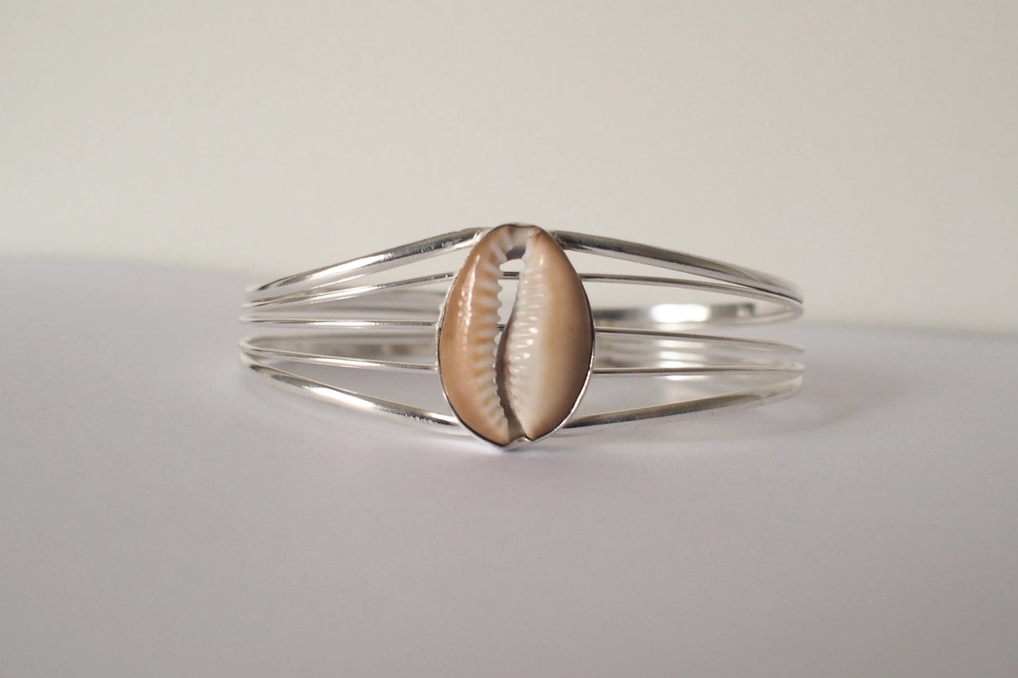 Silver bracelet with a cowrie shell on a light gray background