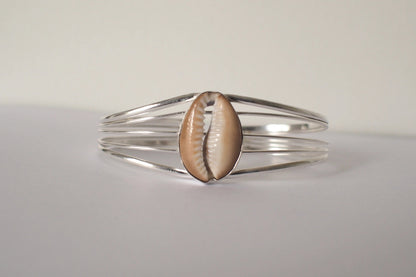 Silver bracelet with a cowrie shell on a light gray background